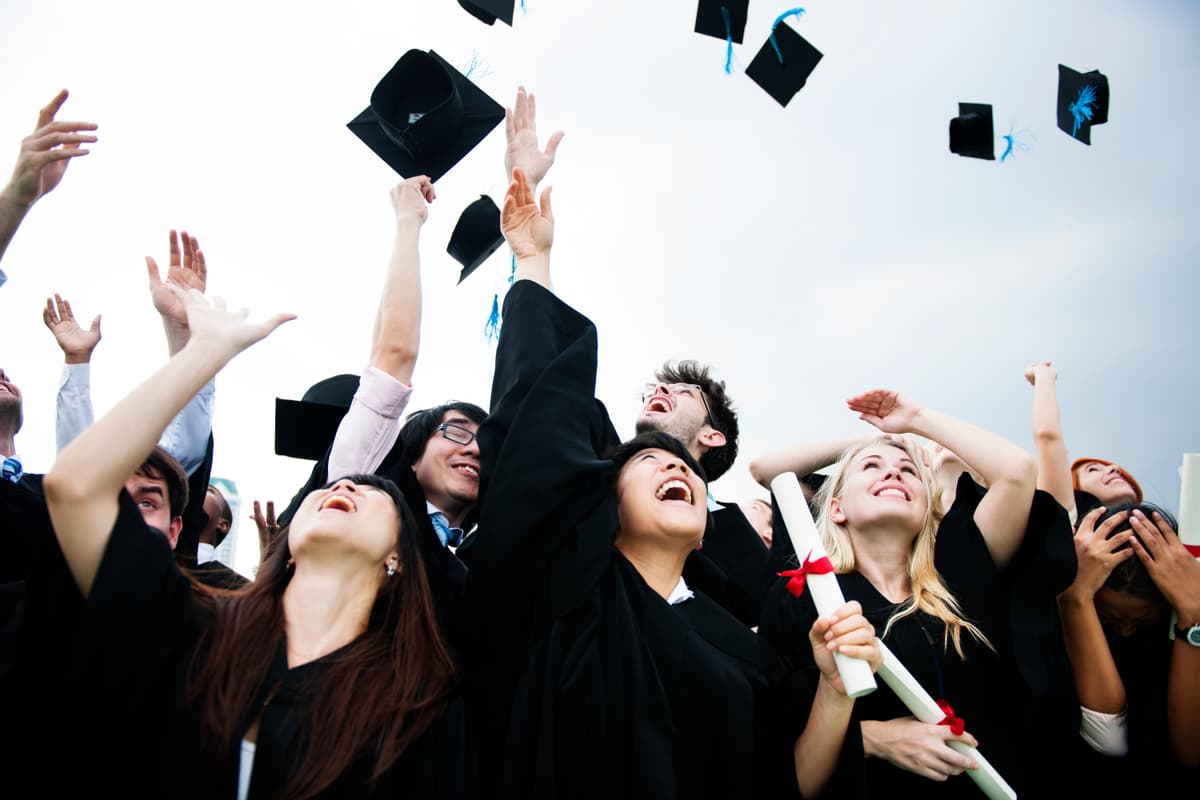 Diverse graduates throwing caps up in the sky
